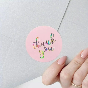 Macro shot of a holographic Thank You sticker on a pink round label sealing a paper envelope