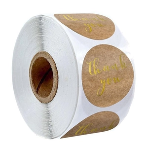 Detail of round kraft paper thank you stickers with gold foil cursive on a roll