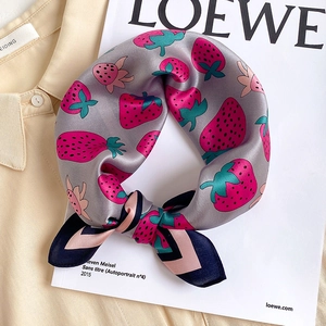 Detail of silk scarf showing pink strawberry print and elegant contrast border ribbon