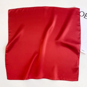 Close-up of bright red silk square scarf with satin finish and neat machine-stitched edges