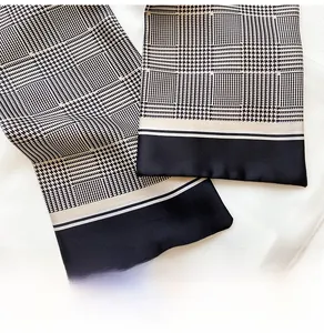 Detail of elegant houndstooth and plaid silk scarf with smooth texture and black borders