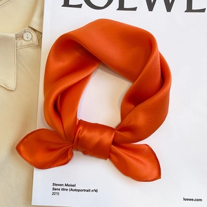 Close-up of bright orange pure silk square scarf with satin finish on fashion magazine