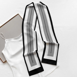 Detail view of a thin white twilly scarf with black geometric stripes on a white top