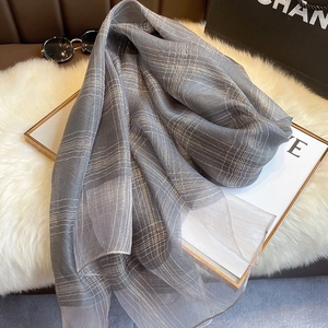 Detail of silk blend scarf with gold metallic threads and plaid pattern on faux fur