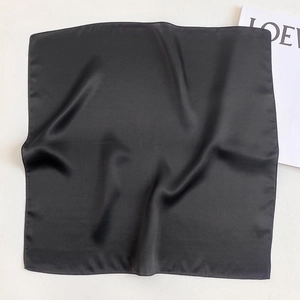 Detailed view of black silk scarf showing smooth satin texture and neat hemmed edges