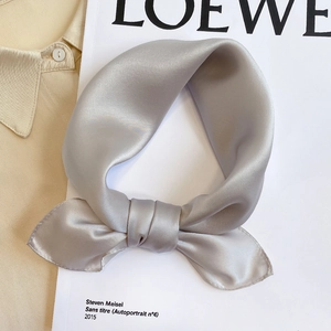 Detailed view of silver grey silk scarf tied in a bow with elegant glossy texture