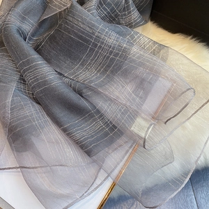 Close-up of gray silk blend scarf featuring metallic silver lurex stripes and fine texture
