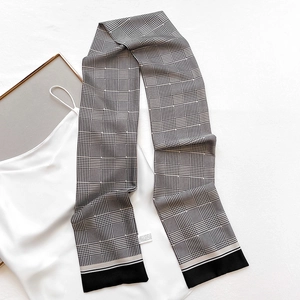 Detail of narrow houndstooth silk scarf on white dress showing texture and pattern