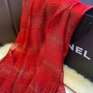 Detail of red silk blend scarf featuring elegant metallic gold stripes and soft texture