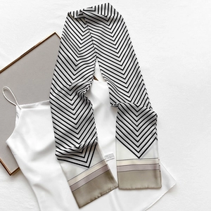 Close-up of narrow silk scarf with V-shaped geometric stripes on white camisole