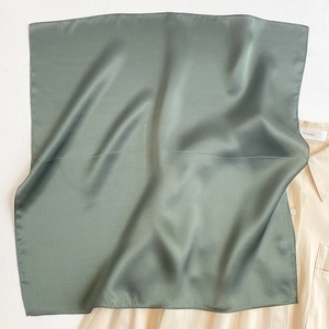 Detailed view of sage green silk square scarf with fine edge stitching and smooth texture