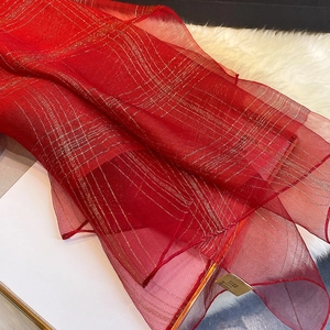 Macro shot of red silk blend scarf featuring metallic gold thread plaid and sheer texture