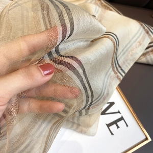 Détail du tissu transparent en mélange de soie avec rayures dorées métallisées à carreaux