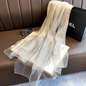 Detailed view of grey silk blend scarf with elegant silver vertical stripes on a sofa