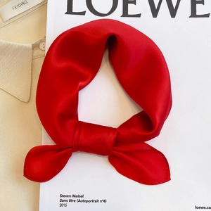 Detail of red silk square scarf with satin luster knotted on a beige shirt collar