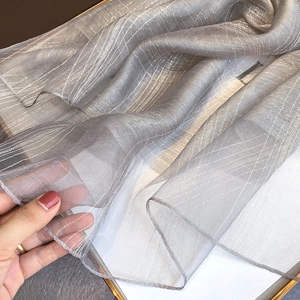 Detail of silver silk blend scarf showing sheer pleated texture and metallic luster