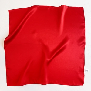 Detail of red square silk scarf showing 100% mulberry silk label and satin texture