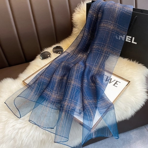 Detail of dark blue silk blend scarf featuring metallic gold thread grid on plush background