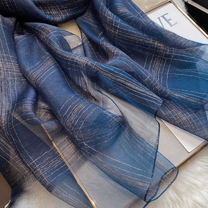 Detailed view of navy blue silk scarf with shimmering gold metallic thread stripes