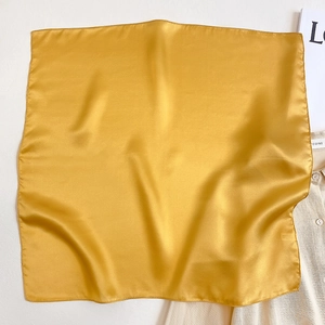 Detail view of mustard yellow silk square scarf with soft pearl luster and fine stitching