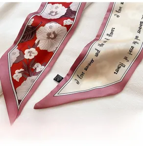 Detail eines schmalen Blumenschals mit Textaufdruck und Polyester-Waschetikett