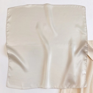 Detail of champagne silk scarf showing smooth satin texture and fine stitched edges