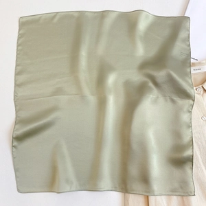 Detailed view of sage green silk square scarf with satin finish and smooth texture