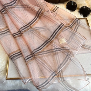 Détail de l'écharpe rose à carreaux en soie avec fil doré brillant et bordure à franges