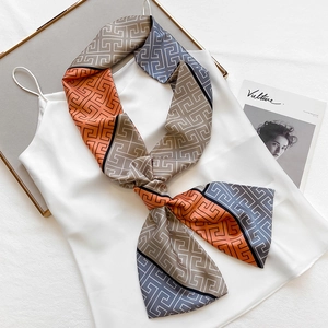 Narrow silk scarf with geometric maze pattern worn as a stylish neck tie on a white top
