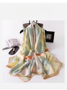 Detail of luxury silk scarf with yellow leaf patterns draped over a stylish handbag