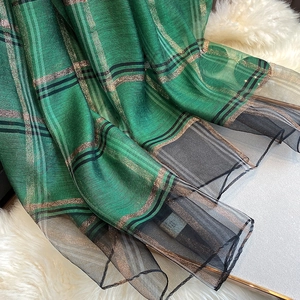 Détail de l'écharpe en soie mélangée à carreaux verts avec fils dorés et tulle