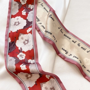Detail eines schmalen Seidenschals mit Hibiskusmuster und eleganter englischer Schrift