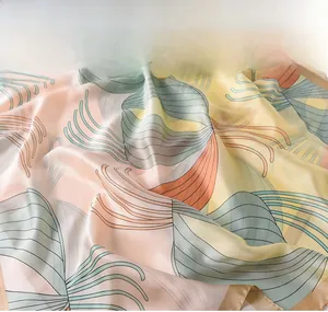 Close-up of lightweight silk-like scarf with abstract patterns in pink, yellow, and green