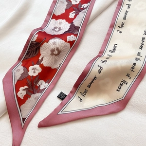 Detail eines doppelseitigen schmalen Seidenschals mit Blumen- und Buchstabendruck und Etikett