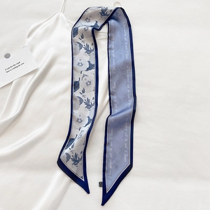 Detail eines blauen floralen Seidenschals mit eleganter Schrift auf weißem Satinkleid