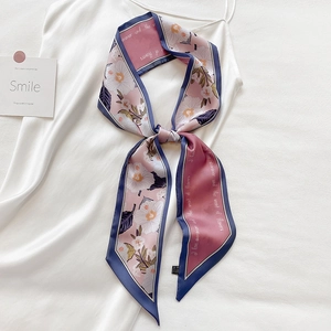 Eleganter rosa Seidenschal mit Blumenmuster und blauem Rand an einem weißen Kleid gebunden
