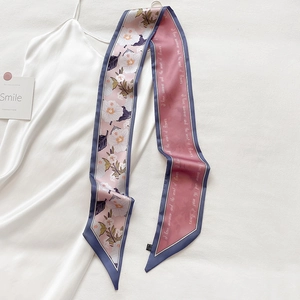 Detail eines floralen Seidenschals mit eleganter Schrift auf weißem Satinkleid-Hintergrund