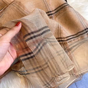 Détail d'une écharpe à carreaux en mélange de soie avec de fins fils dorés brillants