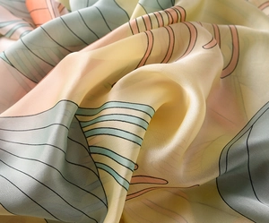 Close-up of lightweight silk scarf fabric with pastel floral patterns and smooth satin texture