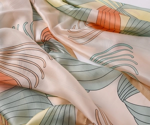 Macro detail of silk scarf showing smooth satin texture and elegant abstract floral print