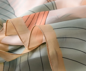Detailed close-up of color-block silk scarf with fine stitching in mint and orange