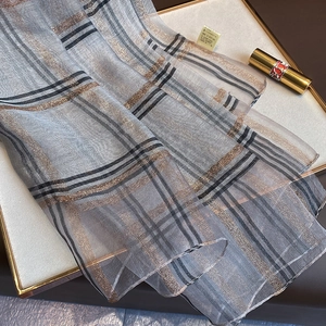 Détail macro de l'écharpe en soie mélangée à carreaux avec fils métalliques