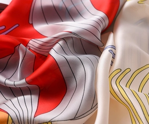 Detail of silk-like scarf showing luxury red and beige pattern with smooth texture