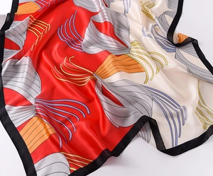 Close-up of elegant silk scarf with red and white color block and abstract line patterns