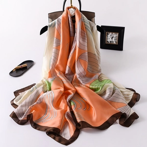 Elegant shell pattern silk scarf in orange and beige draped over a stylish handbag