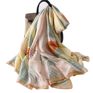 Elegant silk scarf with abstract floral lines draped on a tan leather handbag