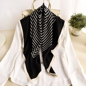 Elegant black and white striped silk scarf draped on a white shirt in a chic setting