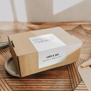 Brown kraft paper gift box with white Thank You sleeve on vintage wooden background