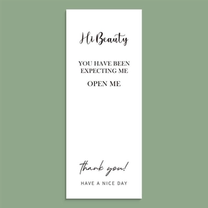 Close-up of a white rectangular thank you gift sticker on a sage green background