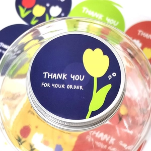 Close-up of blue tulip thank you stickers used as a round seal on a glass jar lid